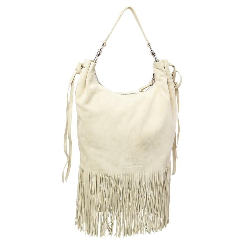 This Miu Miu handbag is an example of the brand's fine designs that are skillfully crafted to project a timeless charm. The hobo is made of light beige suede and enhanced with fringes, a single handle, and a spacious nylon interior.

