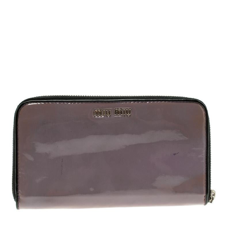 Every woman deserves to have a beautiful wallet in her collection. Crafted from patent leather this Miu Miu wallet features a bow detail on the front. The zip around wallet opens to a leather lined interior that houses two open compartments for