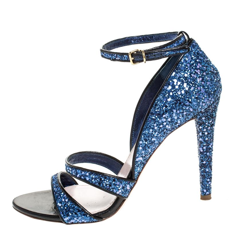 Wear these Miu Miu sandals and add a touch of glamour to any outfit. Crafted from coarse glitter fabric, these metallic blue sandals are edgy and will make your feet look pretty. They come with two front straps, buckled ankle straps, extended