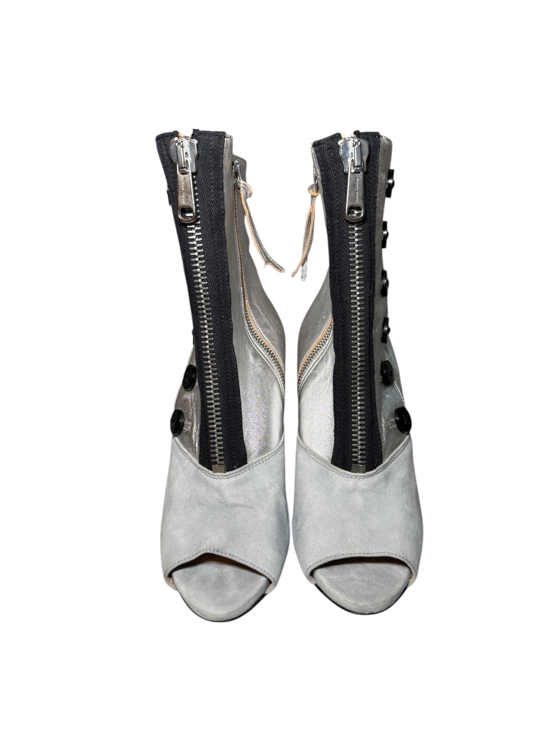 Miu Miu, stivaletti con bottoni in camoscio grigio e argento metallizzato, Resort 2010

Una rara silhouette architettonica proveniente dalle passerelle di Miu Miu dei primi anni 2010, questi stivaletti in pelle argento metallizzato e camoscio grigio