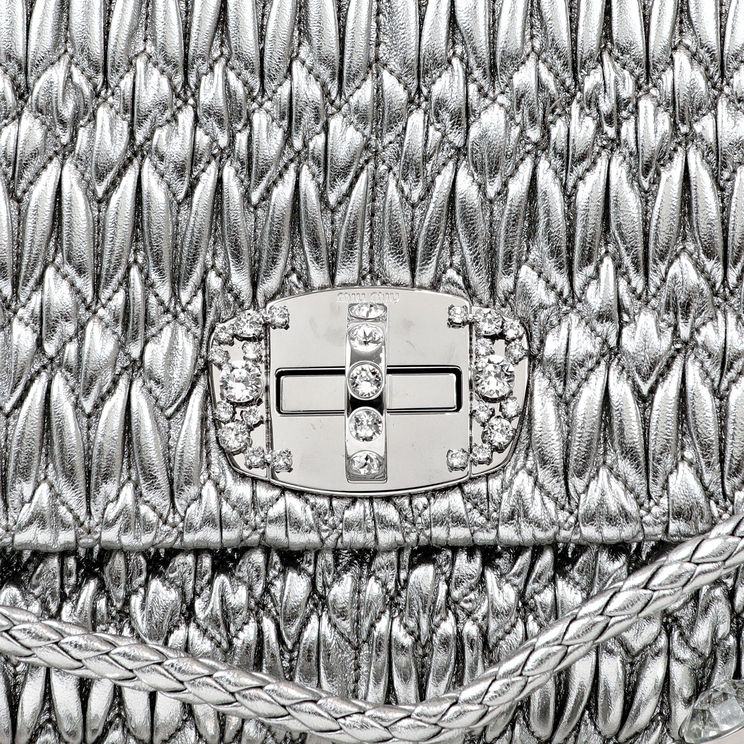 This authentic Miu Miu Metallic Silver Crystal Cloquè Large Bag is in pristine condition.  The iconic design features metallic silver quilted Nappa leather and a crystal turn lock closure.  May be carried by the detachable leather strap or the