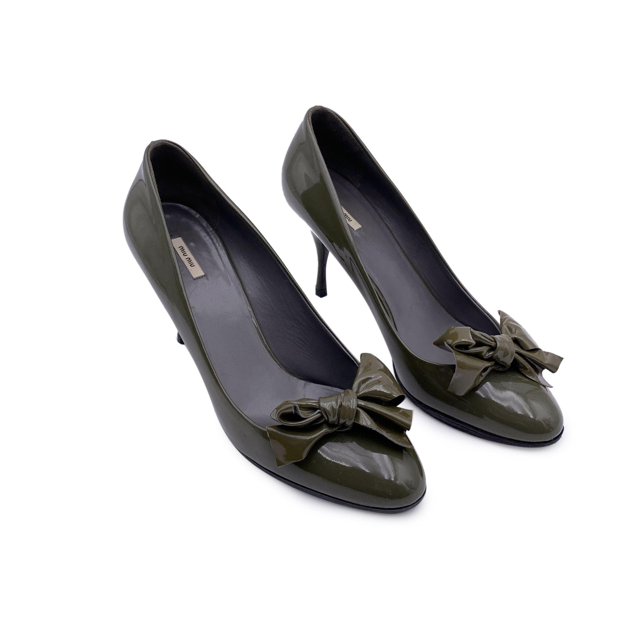 Geschlossene Zehenpumps von Miu Miu. Gefertigt aus grünem Lackleder im Militärstil. Sie haben eine mandelförmige Zehenpartie, sind zum Hineinschlüpfen, haben eine Schleife an der Zehenpartie und einen überzogenen Absatz. Innensohle und Laufsohle aus