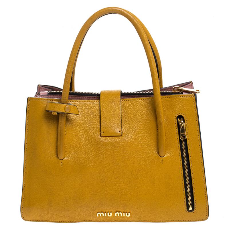 This elegant Madras tote from Miu Miu will make a valuable addition to your collection. The tote is crafted from mustard leather and features a leather tag. It has dual round handles, a flap closure that opens to a suede-lined interior, the gussets