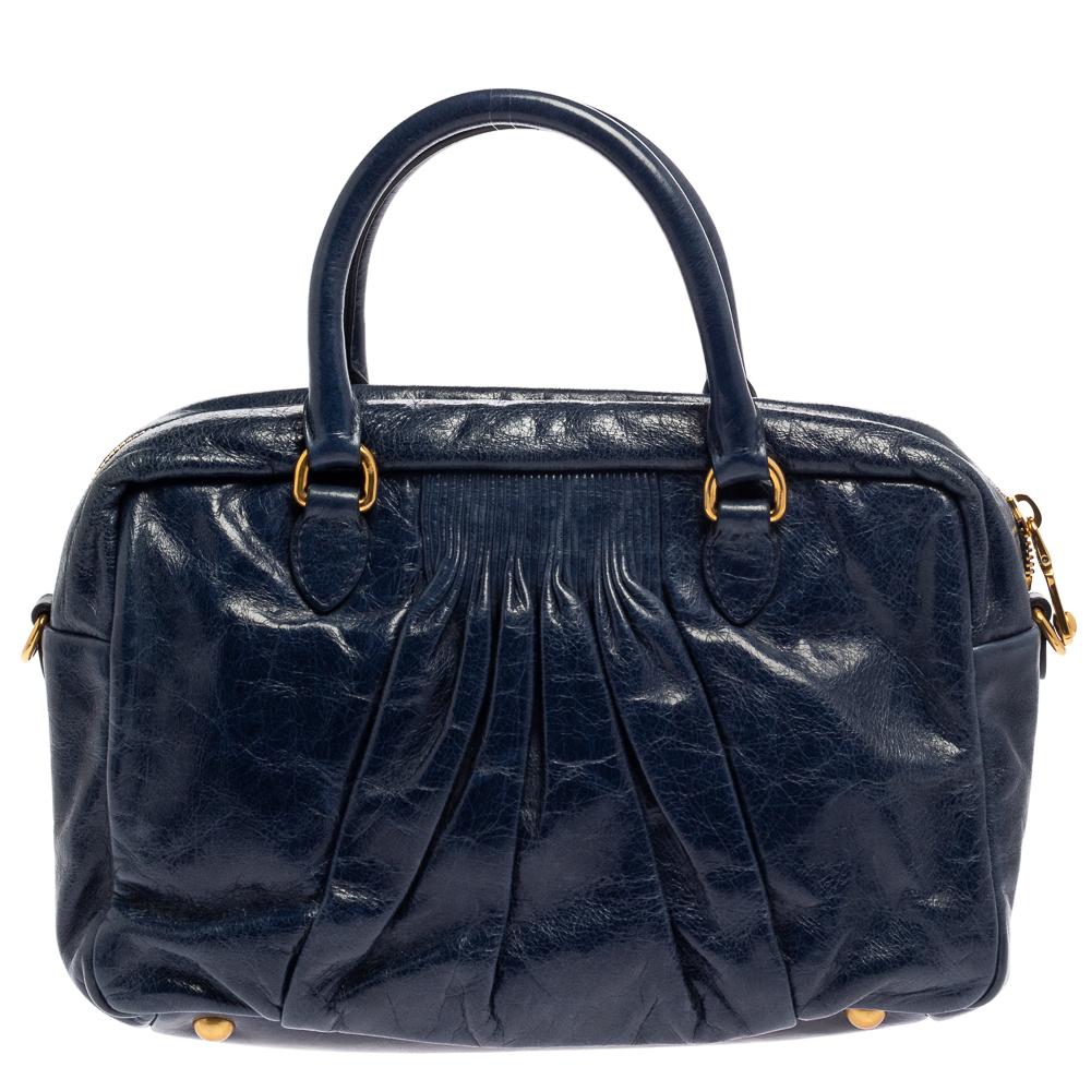 Designed with precision and skill, Miu Miu's satchel exudes style, simplicity, and elegance in equal measures. The bag is crafted from leather in a navy blue shade, it features a pleated design and a capacious main compartment secured by a zip