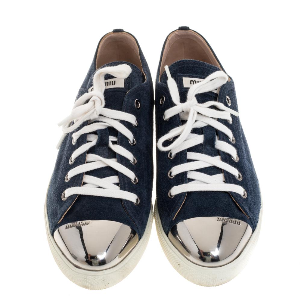 Add some distinct style to your everyday casual wear looks with these stunning Miu Miu lace-up sneakers. Constructed in navy blue suede, these sneakers are accented with silver-tone metal cap toes, further featuring accented with the brand's name on