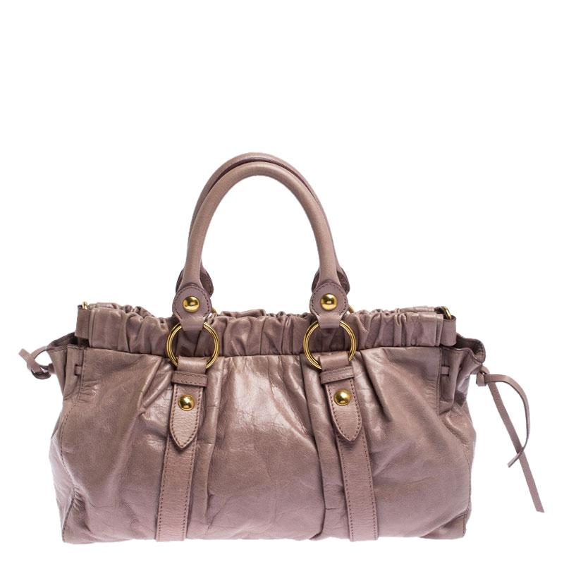 Displaying the brand's creativity and vision, this Miu Miu tote is crafted with lux leather in pink color. It is designed in an interesting gathered style and has dual top handles and a detachable shoulder strap. The bag comes with a satin-lined
