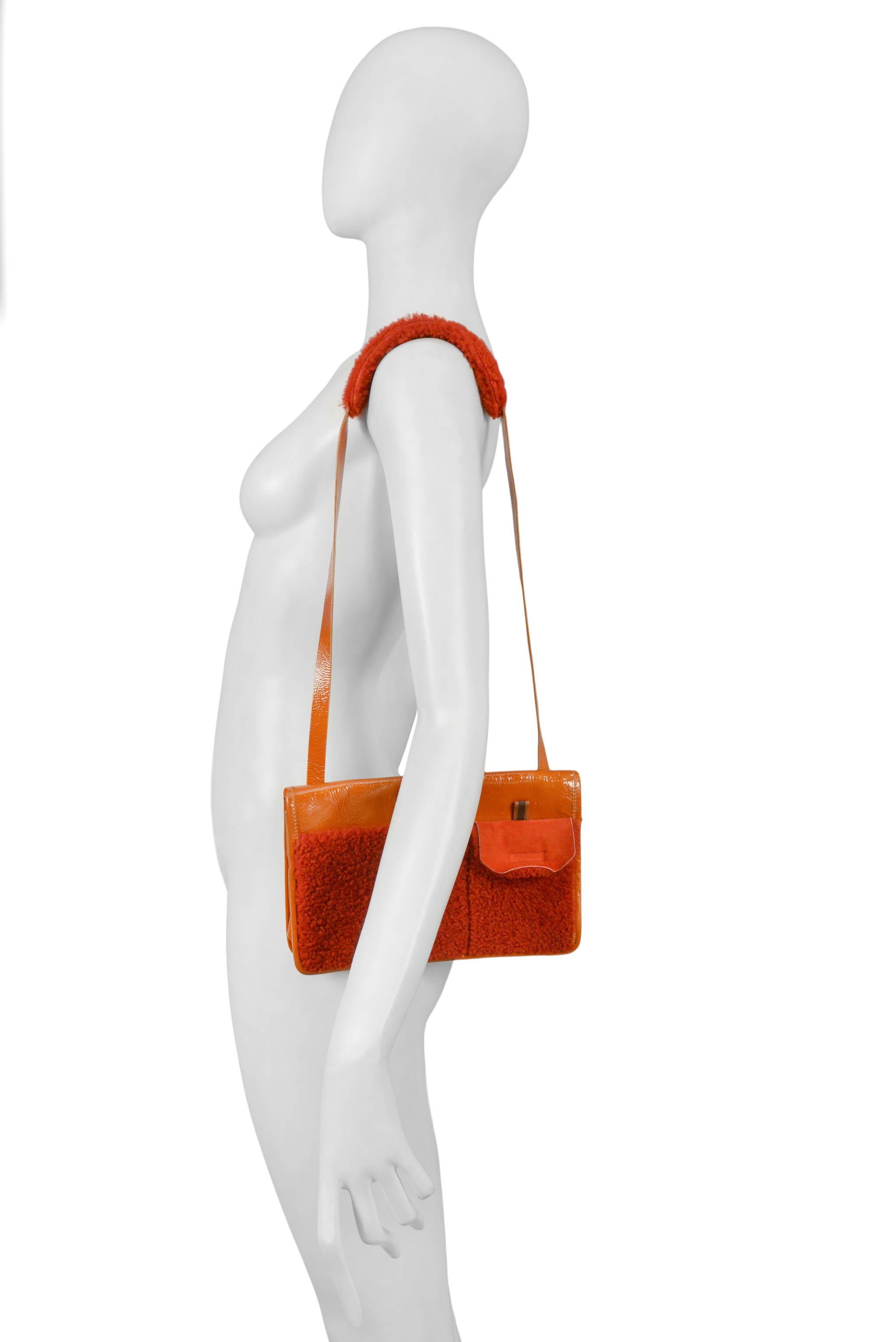 Resurrection Vintage is excited to offer a vintage 1990s Miu Miu red and orange patent leather and shearling shoulder bag featuring small pocket with velcro closure, back slit pocket with velcro closure, shearling shoulder pad, and nylon interior