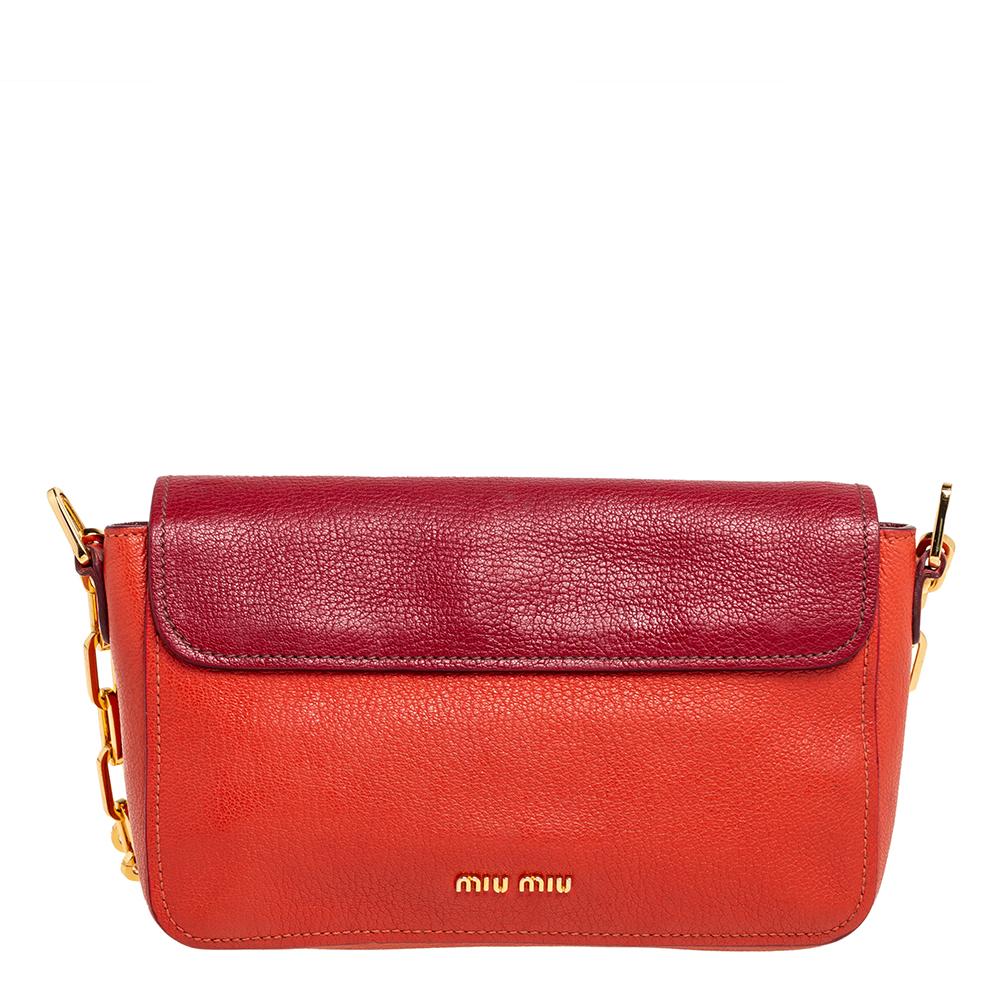 This stunning Madras shoulder bag from the House of Miu Miu is crafted skillfully with precise attention to detail. It is created using orange-red leather on the exterior, with a gold-toned logo-engraved lock closure on the front. It has a