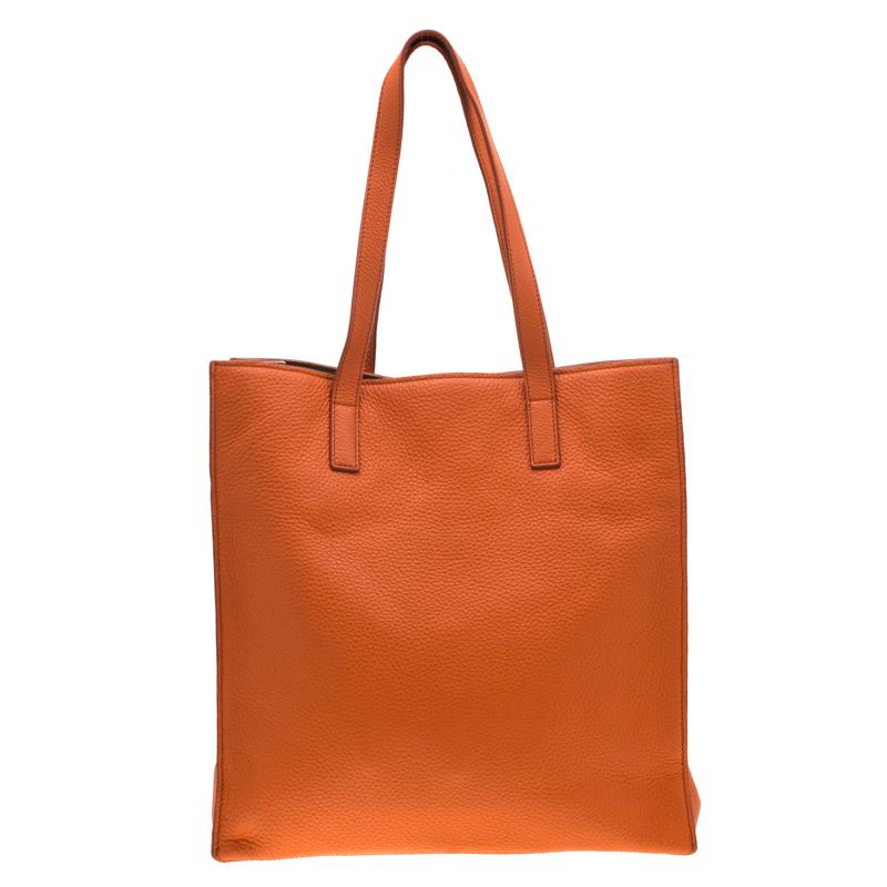 The shopper tote is crafted from leather and features a spacious satin interior that ensures to house more than just your essentials. Complemented with gold-tone hardware, this orange creation is designed by Miu Miu. This durable tote will fit all