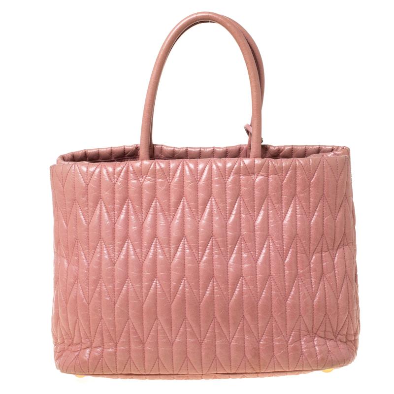 This Miu Miu tote boasts of a durable finish and offers style and utmost practicality. Crafted from leather it features dual handles, a shoulder strap and gold-tone hardware. The satin-lined interior has two open compartments and a zipped