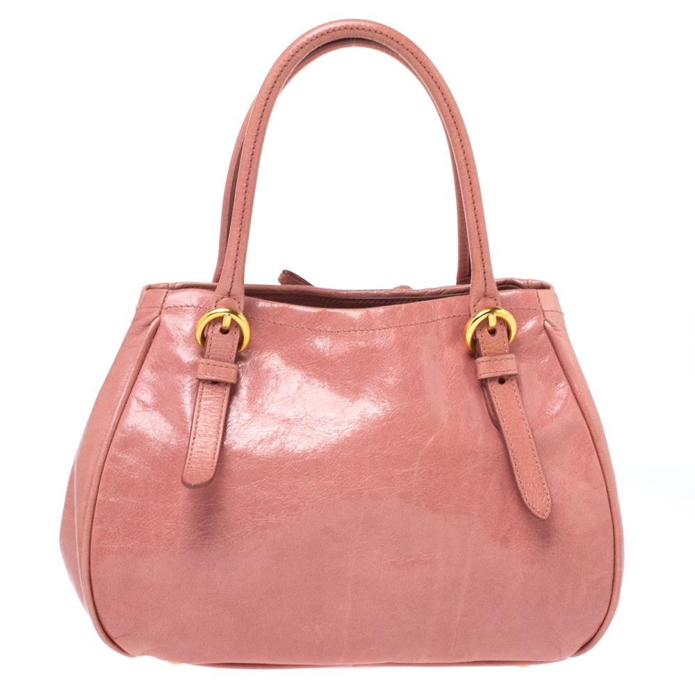 This Miu Miu handbag promises to help you stay stylish from day to night and weekday to weekend. Crafted from pink leather, this bag is equipped with two handles and a detachable shoulder strap and flaunts a bow detailing on the front.

