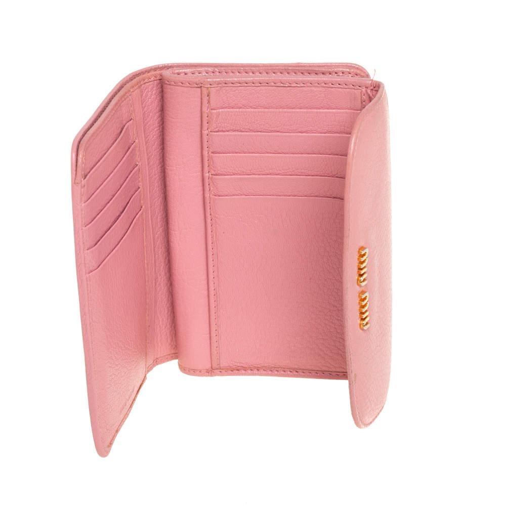 Accessorizing gets a new avatar with this chic Madras wallet from Miu Miu. It comes crafted from pink leather and features gold-tone brand logo detailing on the front flap. It opens to a leather and fabric interior that houses a zip pocket and