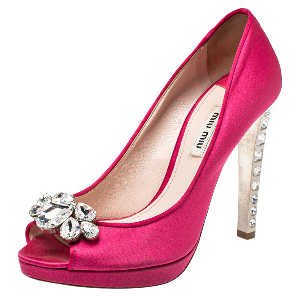 Mit diesen Plateau-Pumps von Miu Miu sind Sie bereit, die Massen zu beeindrucken! Die rosafarbenen Pumps sind aus Satin gefertigt und wirken mit ihrer fabelhaften Silhouette ätherisch. Sie haben eine Peep-Toe-Spitze mit Kristallverzierungen, eine