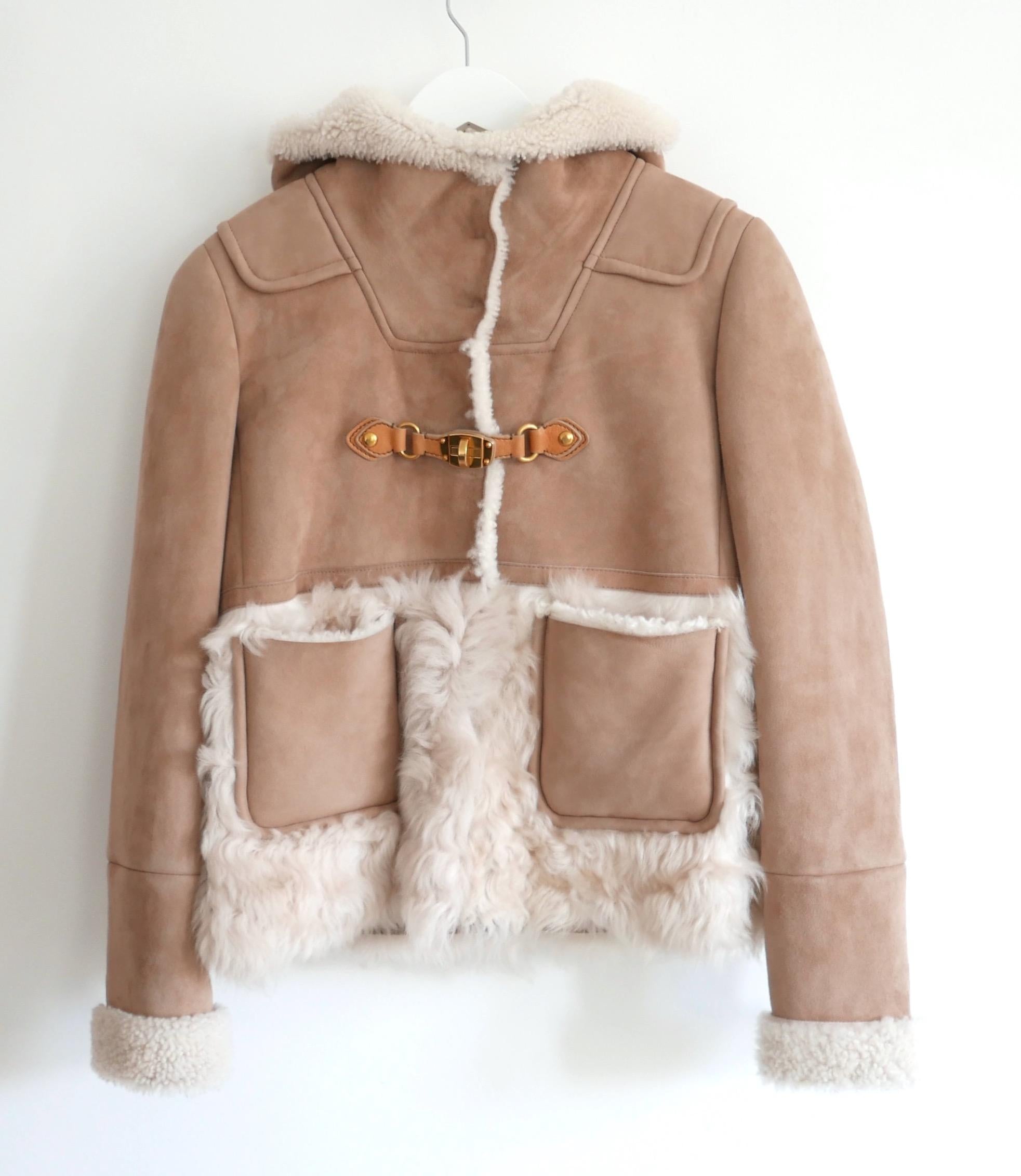 Gorgeous archival Miu Miu Pre-Fall 2010 shearling short coat. bought for £3500 and unworn. Made from super soft camel coloured suede with a thick, fluffy shearing inner, it has feature front pockets, deep hood, optional high neck with poppers and