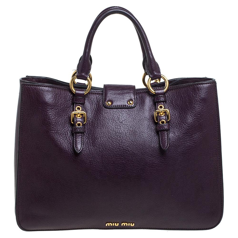 Stunning to look at and durable enough to accompany you wherever you go, this Miu Miu tote bag is a joy to own! This Madras bag is crafted from leather in a purple hue and features a detachable floral charm. Held by dual handles, the creation is