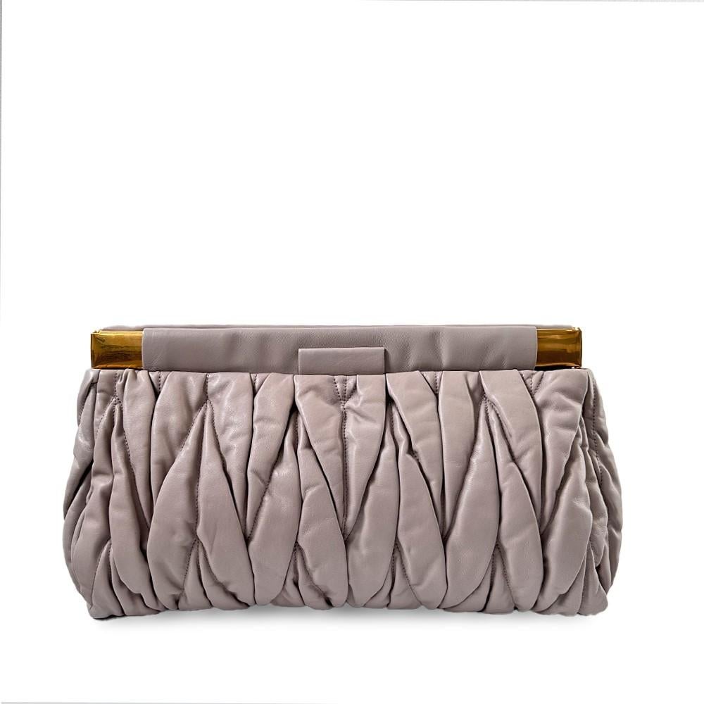 This contemporary Miu Miu clutch is crafted from matelassé leather and features the signature logo, gold tone hardware and spacious double compartment with magnetic closure. Coming in a beautiful 