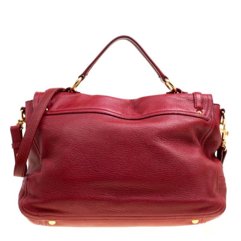 Miu Miu's East/West shoulder bag exhibits the brand's flair to make minimalist designs with subdued elegance. Crafted with red leather, the front exterior is adorned with leather belts detailed with gold-tone metal accents. It is designed with a