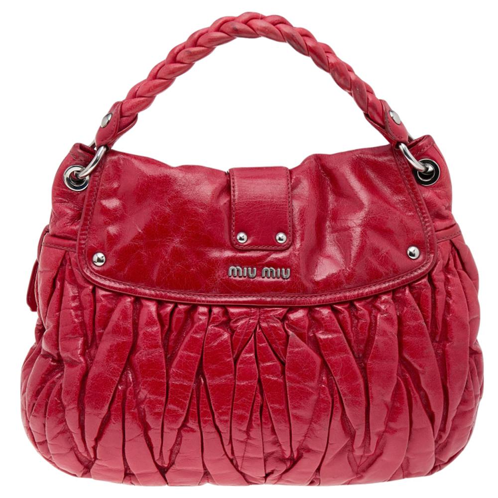 Miu Miu's coffer hobo is crafted from red matelassé leather. The bag features a braided top handle, a detachable shoulder strap, and silver-tone hardware. The metal lock opens to a spacious fabric-lined interior that houses a zip pocket.

Includes: