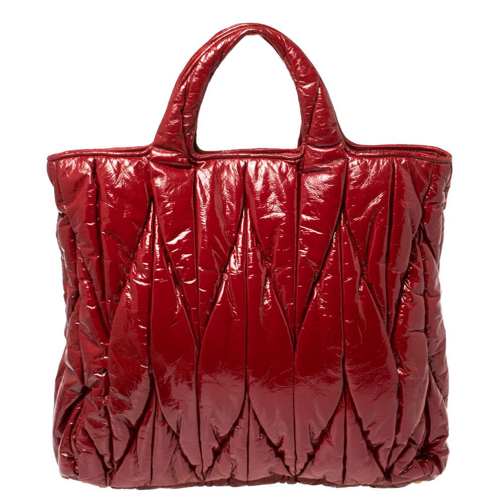 Created from Matelassé vinyl and lined with fabric, this red Miu Miu bag is a fine accessory for all your needs. The North/South tote has a spacious fabric interior, two handles, and a shoulder strap. It is stylish, functional, and luxe.

