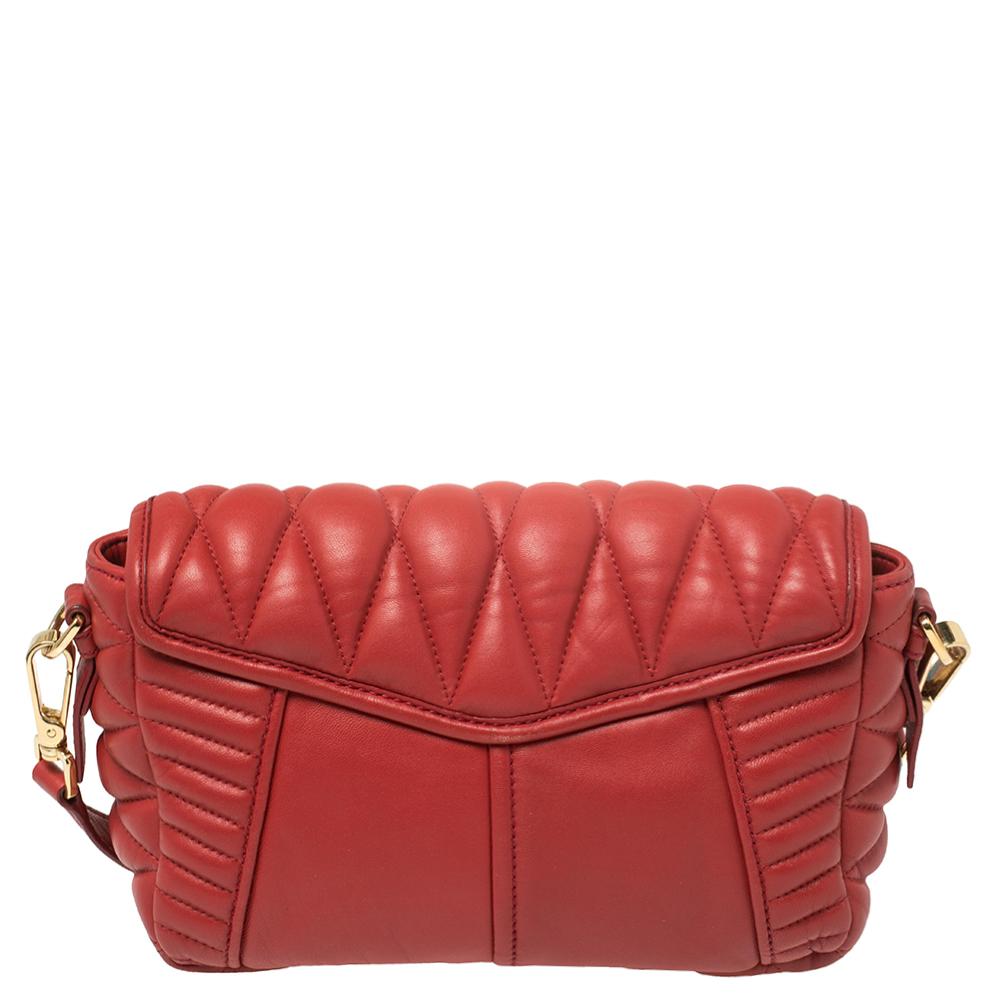 This gorgeous shoulder bag from Miu Miu will make you go head over heels with its artistic design and craftsmanship. Created from red quilted leather, it features a front flap pocket with a gold-tone push-lock closure. The top zip opens to a