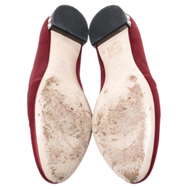 Diese auffälligen Slipper von Miu Miu wurden aus rotfarbenem Satin gefertigt. Sie sind mit schönen schwarzen Stickereien auf dem Vorderblatt versehen und die Absätze sind mit Kristallnieten verziert. Die Einlegesohlen sind mit Leder gefüttert und in