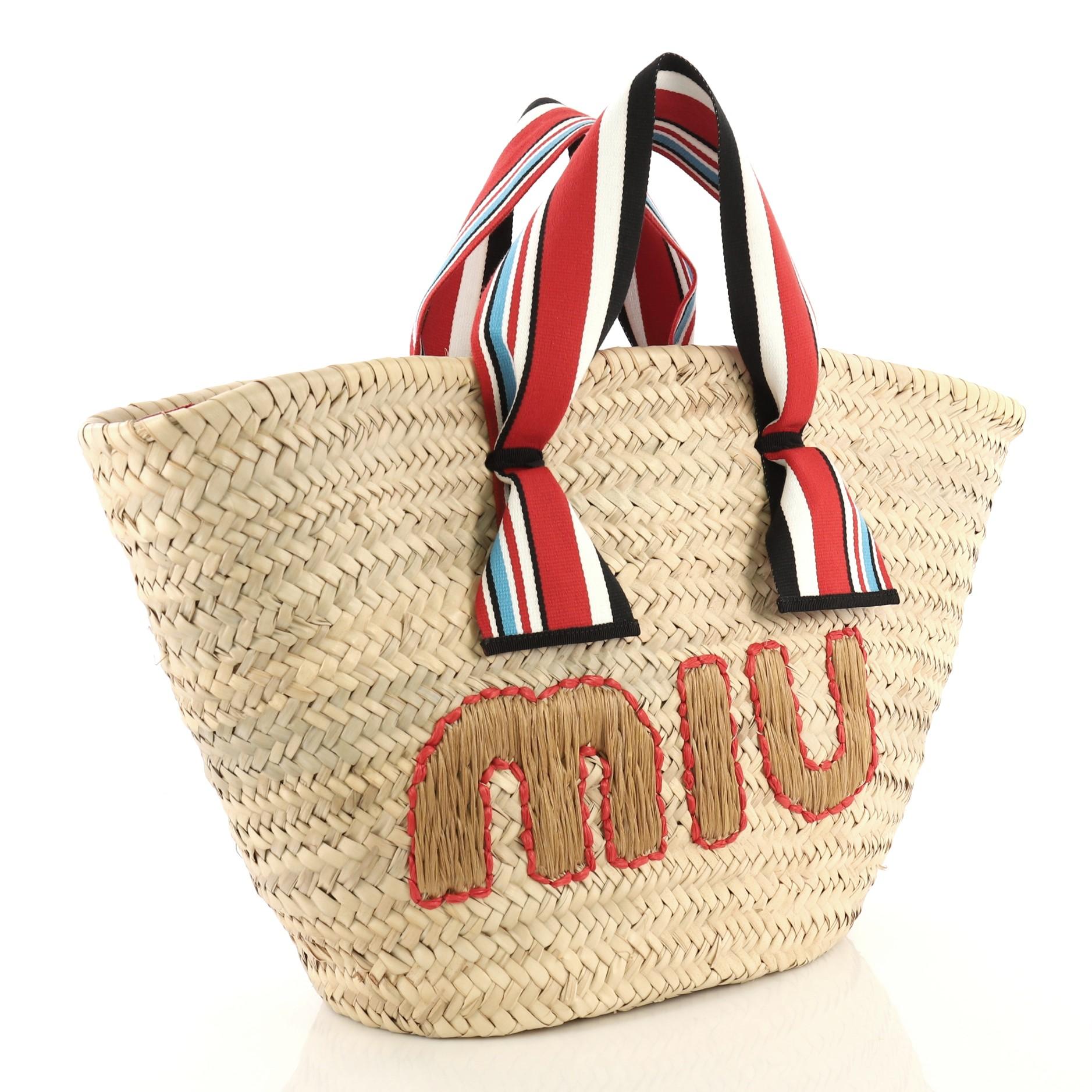 This Miu Miu Ribbon Basket Tote Woven Straw, crafted from neutral woven straw, features striped ribbon handles, embroidered logo at front, and gold-tone hardware. It opens to a neutral fabric interior with side zip pocket.

Estimated Retail Price: