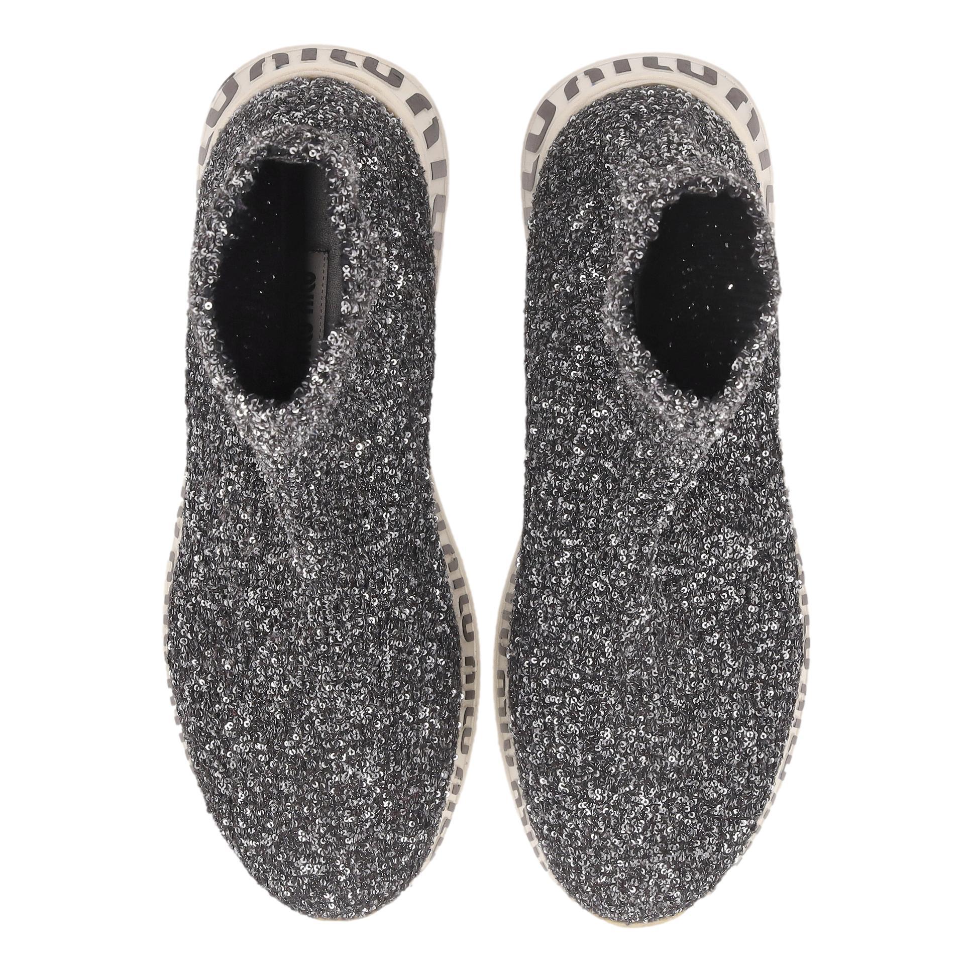 Miu Miu - Chaussettes à logo ornées de paillettes

Baskets montantes en chaussettes stretch gris métallisé/argenté, ornées de paillettes sur tout le pourtour.

Whiting, elles sont dotées d'une semelle blanche ornée du logo Miu Miu noir.

Rrp Approx.