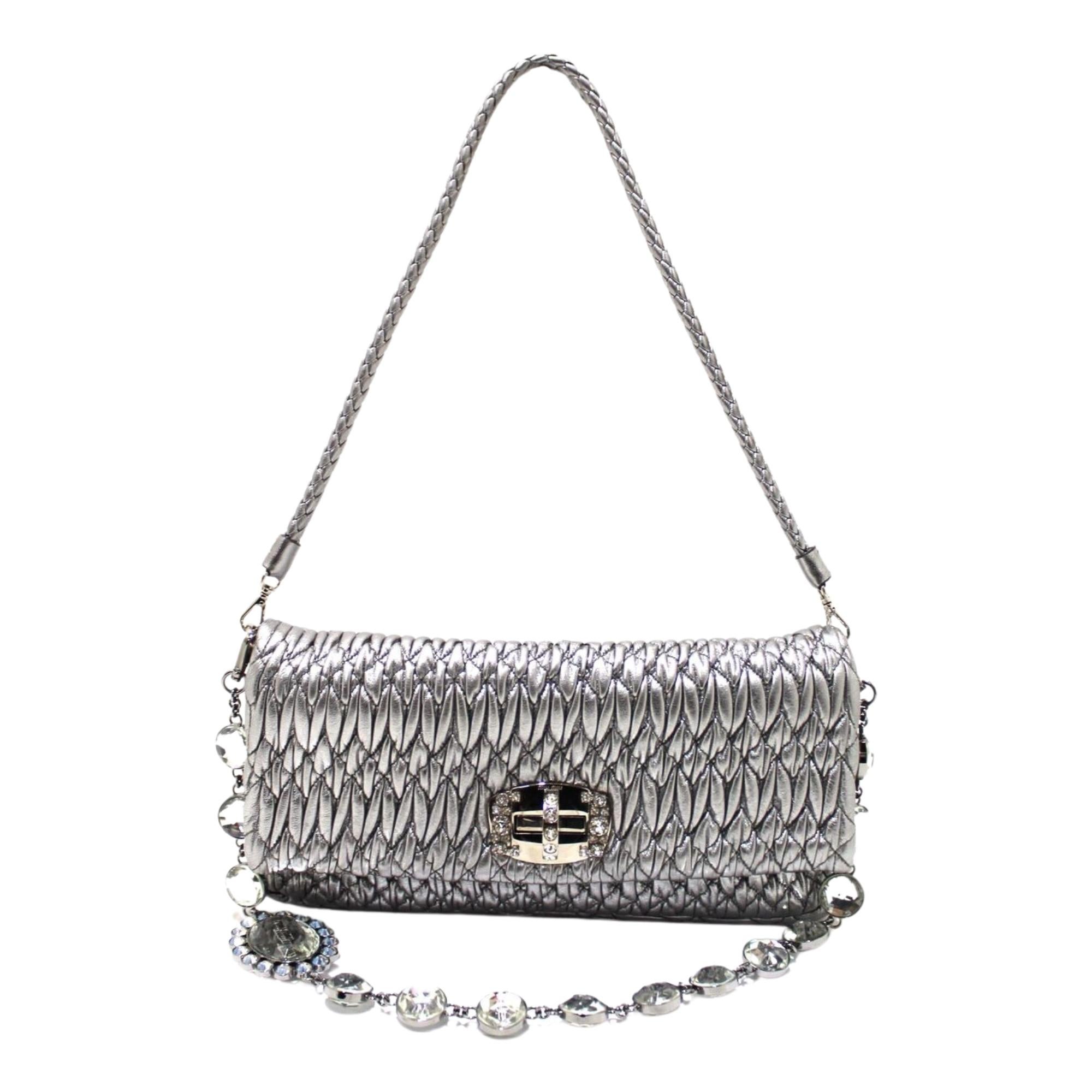 This feminine classic Miu Miu bag is made from the fashion house's signature texture cut from nappa leather with cloquet craftsmanship. The bag features two removable straps including one silver chain shoulder strap with crystal embellishments and a
