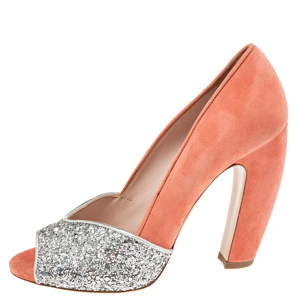 How chic are these pumps from the House of Miu Miu They are designed using silver coral pink coarse glitter and suede on the exterior. They feature peep toes a slip on closure and sturdy heels. Look gorgeous as you walk in these Miu Miu pumps.
