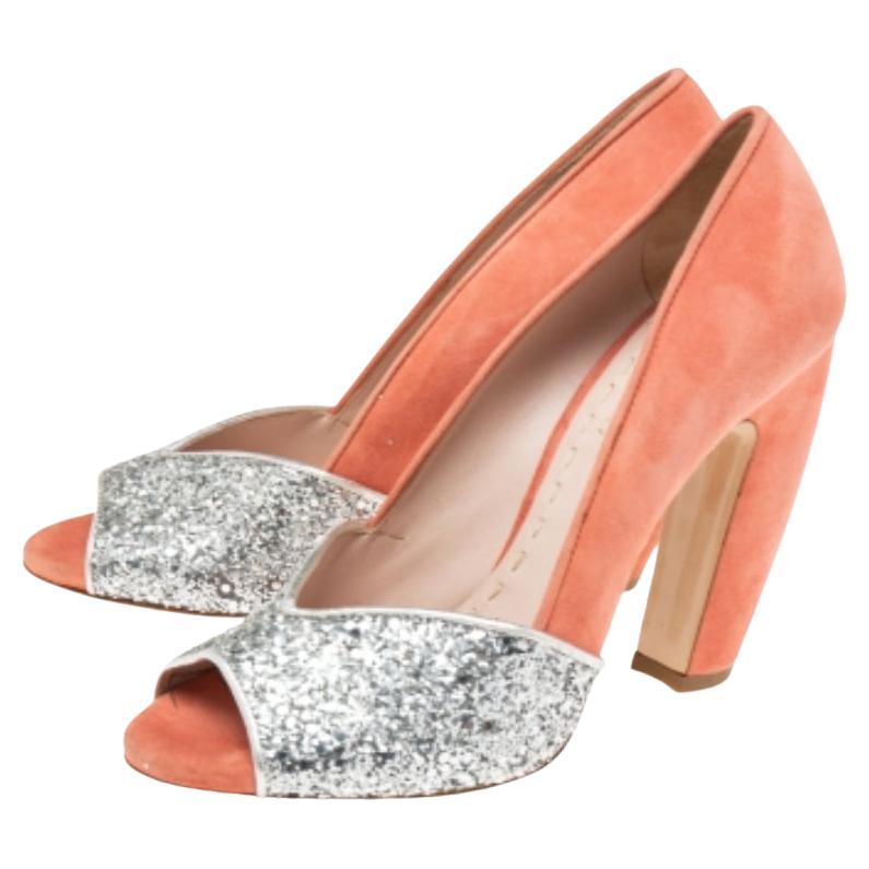 How chic are these pumps from the House of Miu Miu! They are designed using silver, coral-pink coarse glitter and suede on the exterior. They feature peep-toes, a slip-on closure, and sturdy heels. Look gorgeous as you walk in these Miu Miu pumps.