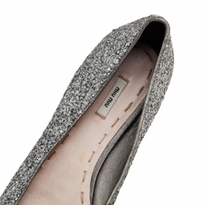 Un paio di Miu Miu per illuminare la tua strada con le scintille. Questo paio di ballerine del marchio è realizzato in glitter argentato e con fiocchi sulla tomaia. Le ballerine sono dotate di solette foderate in pelle e di suole resistenti.
