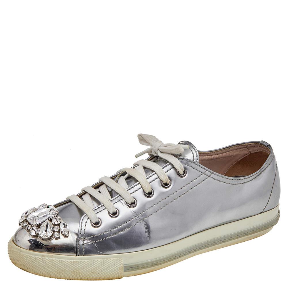 Let your style stand out when you wear these amazing sneakers from the House of Miu Miu. They are luxuriously designed using silver patent leather in a low-top style. They are adorned with lace-ups and crystal-embellished toes. Exude charm and class