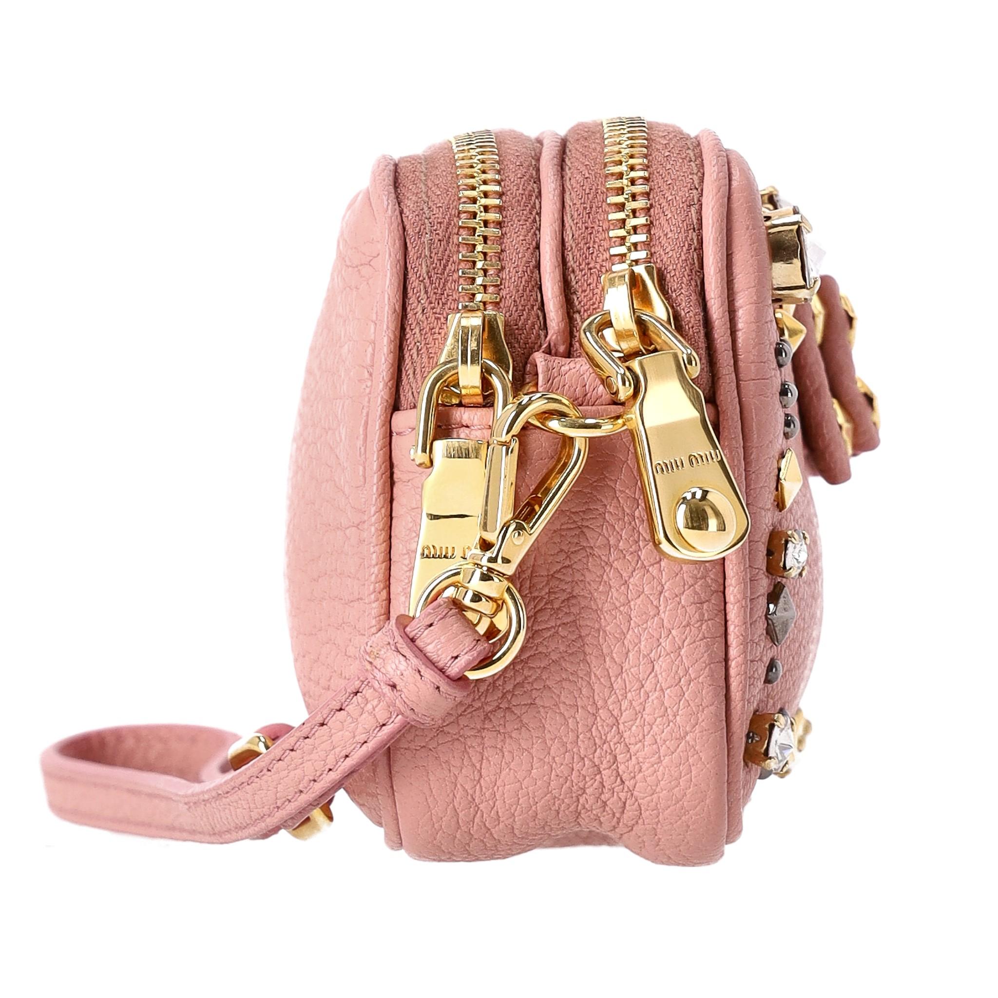 Miu Miu Stud Embellished Leather Pouch/Purse 

Baby pink leather embellished with gold 'Miu Miu' signature and bow detail with multi-stud and crystal design to the front.

Removable, leather side handle and two main top, zipped compartments.

Rrp
