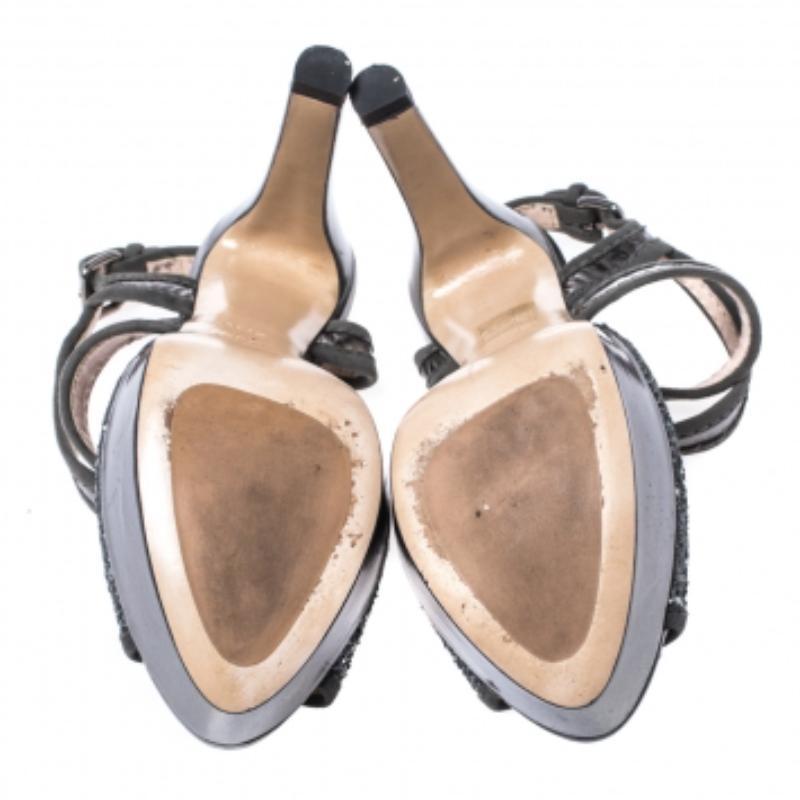 Look glamorous and ready for special occasions instantly with these Miu Miu sandals. They have been crafted from glitter and suede and come in a lovely shade of metallic grey. They have open toes, cross straps, platforms, 12 cm heels, gunmetal-tone