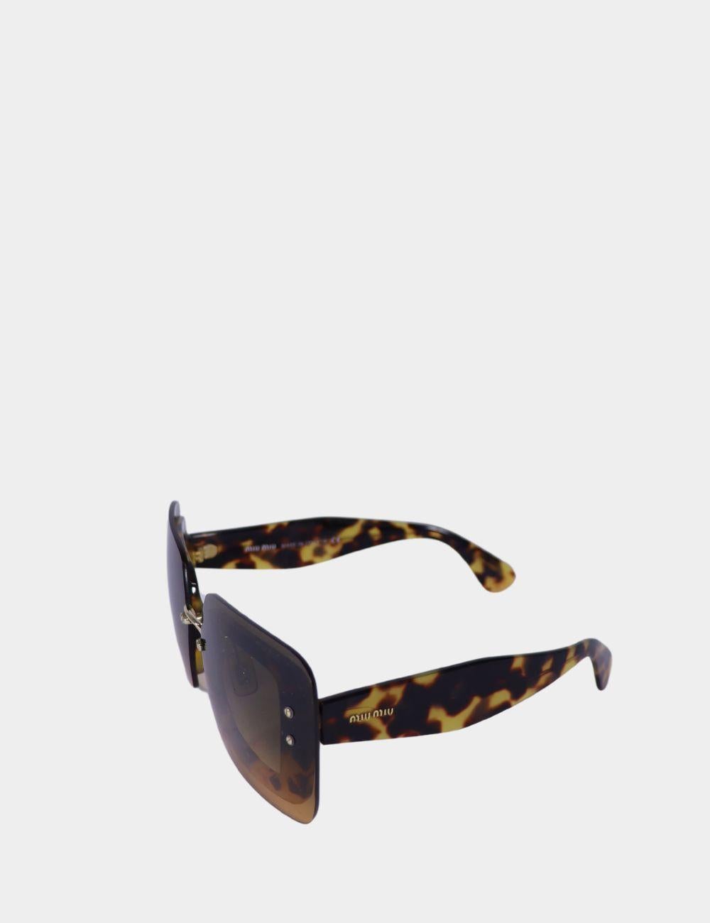 Fai una dichiarazione di moda senza paura con questi occhiali da sole a scudo tartarugati di Miu Miu. Caratterizzati da un audace design a scudo con lente singola e spesse stanghette in acetato con un classico motivo tartarugato, questi occhiali da