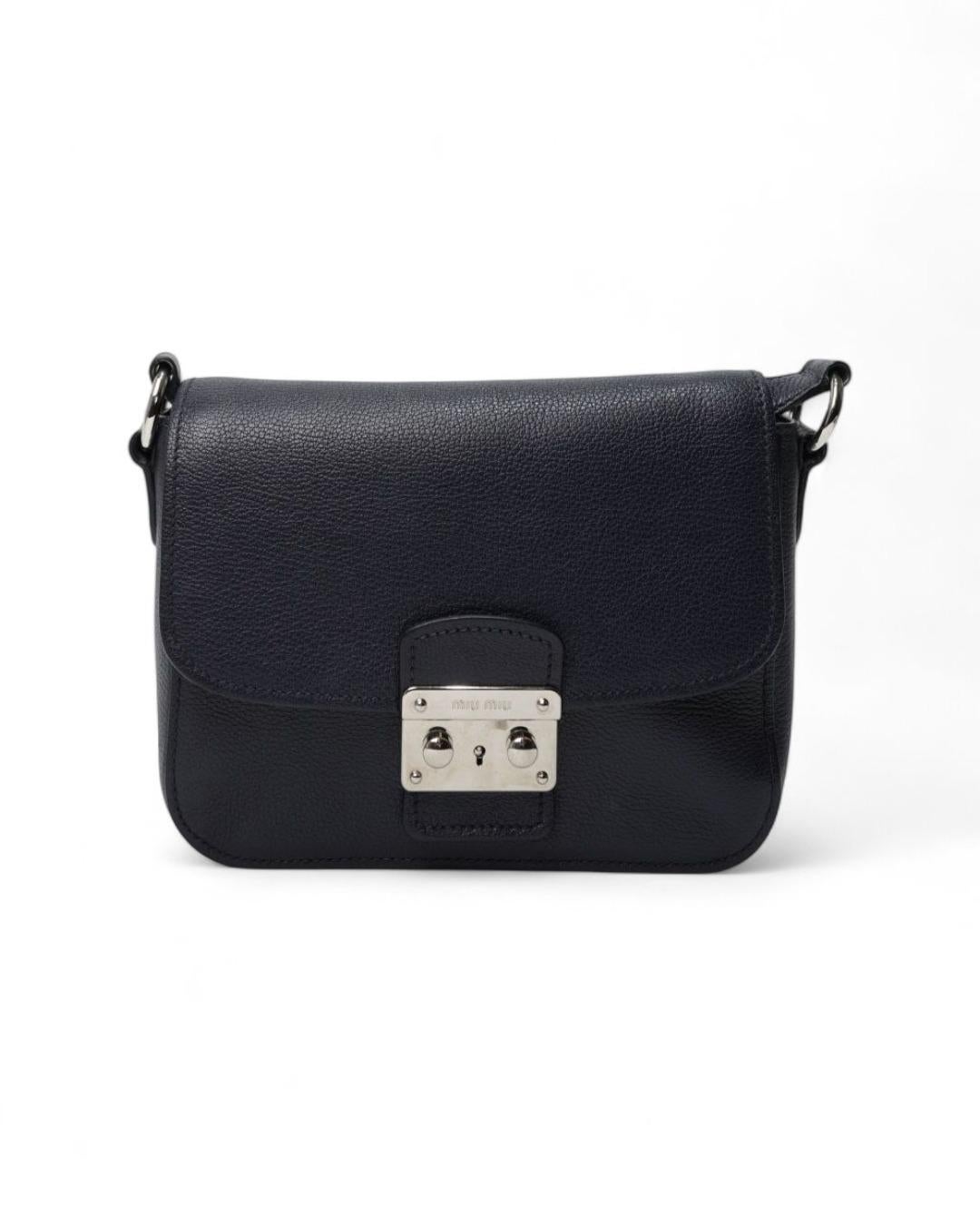Sac Miu Miu, petit format, en cuir grainé bleu avec ferrures argentées. Doté d'un rabat avec fermeture à clip, doublé intérieurement en satin noir avec des poches pratiques, le sac est assez spacieux. Équipé d'une bandoulière réglable pour un