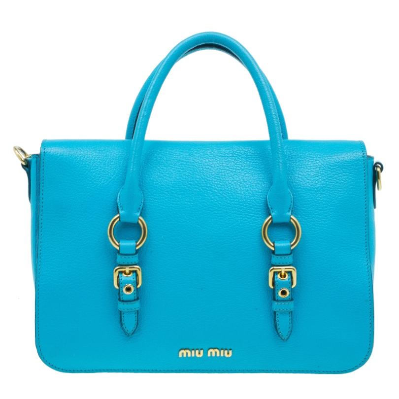 Go for a fresh finish with this Large Madras Flap tote by Miu Miu. Crafted in turquoise blue leather, it comes accented with luxe gold hardware, double rolled top handles and a removable and adjustable shoulder strap. The front flap opens to a