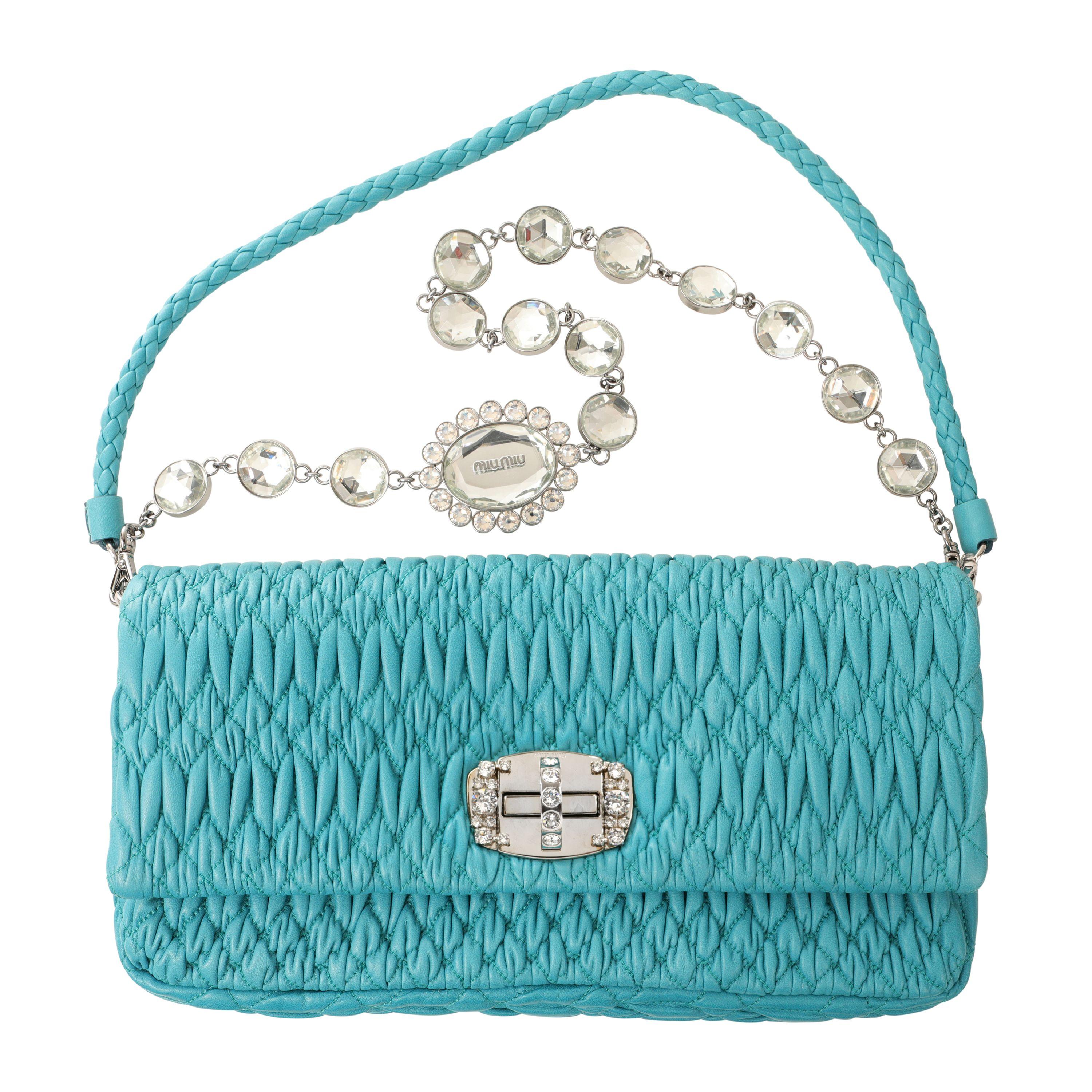 This authentic Miu Miu Turquoise Crystal Cloquè Small Bag is in pristine condition.  The iconic design features turquoise quilted Nappa leather and a crystal turn lock closure.  May be carried by the detachable leather strap or the decorative