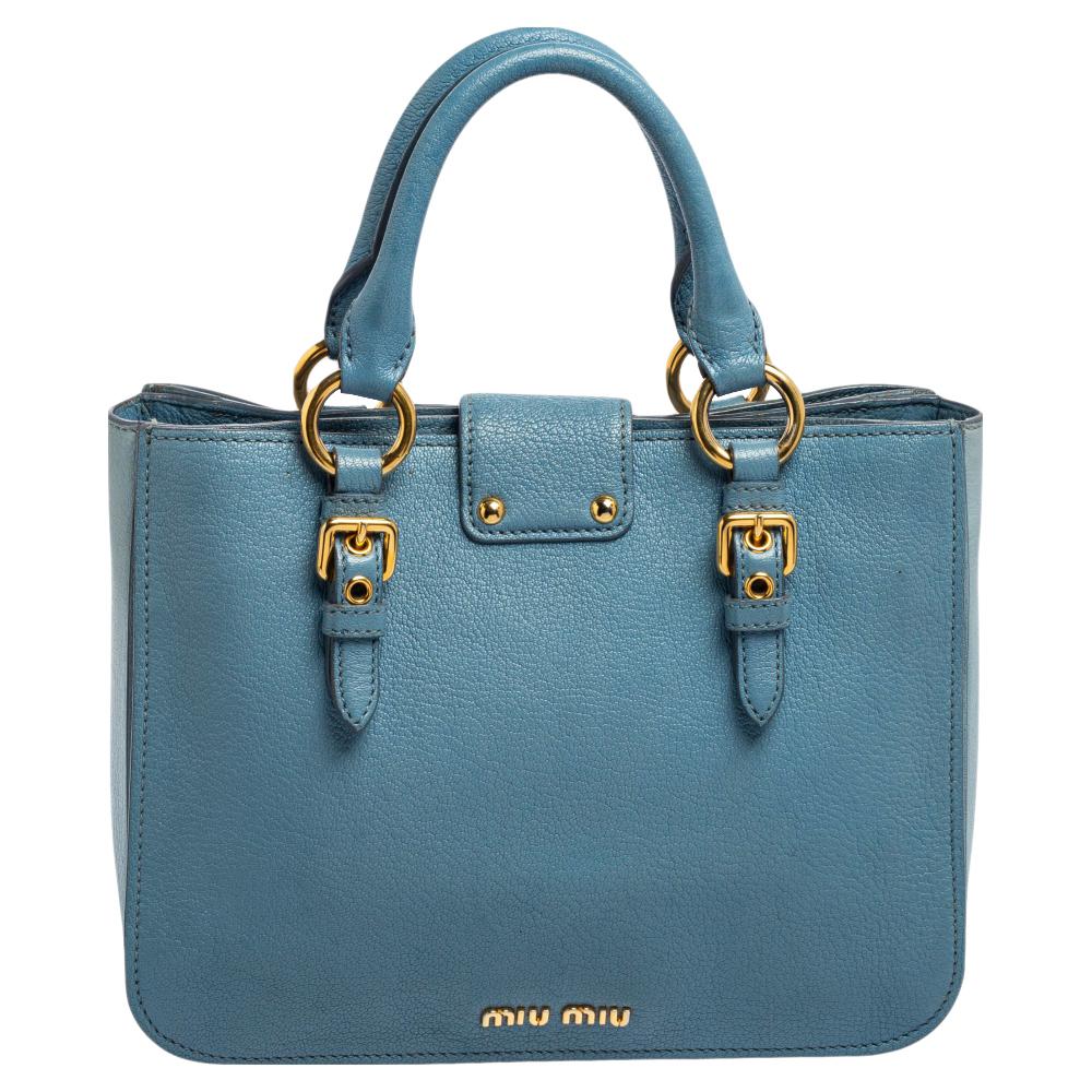 This stunning Madras tote from the House of Miu Miu is crafted skillfully with precise attention to detail. It is created using two-toned blue leather on the exterior and flaunts a gold-toned logo-engraved lock closure on the front. It has a