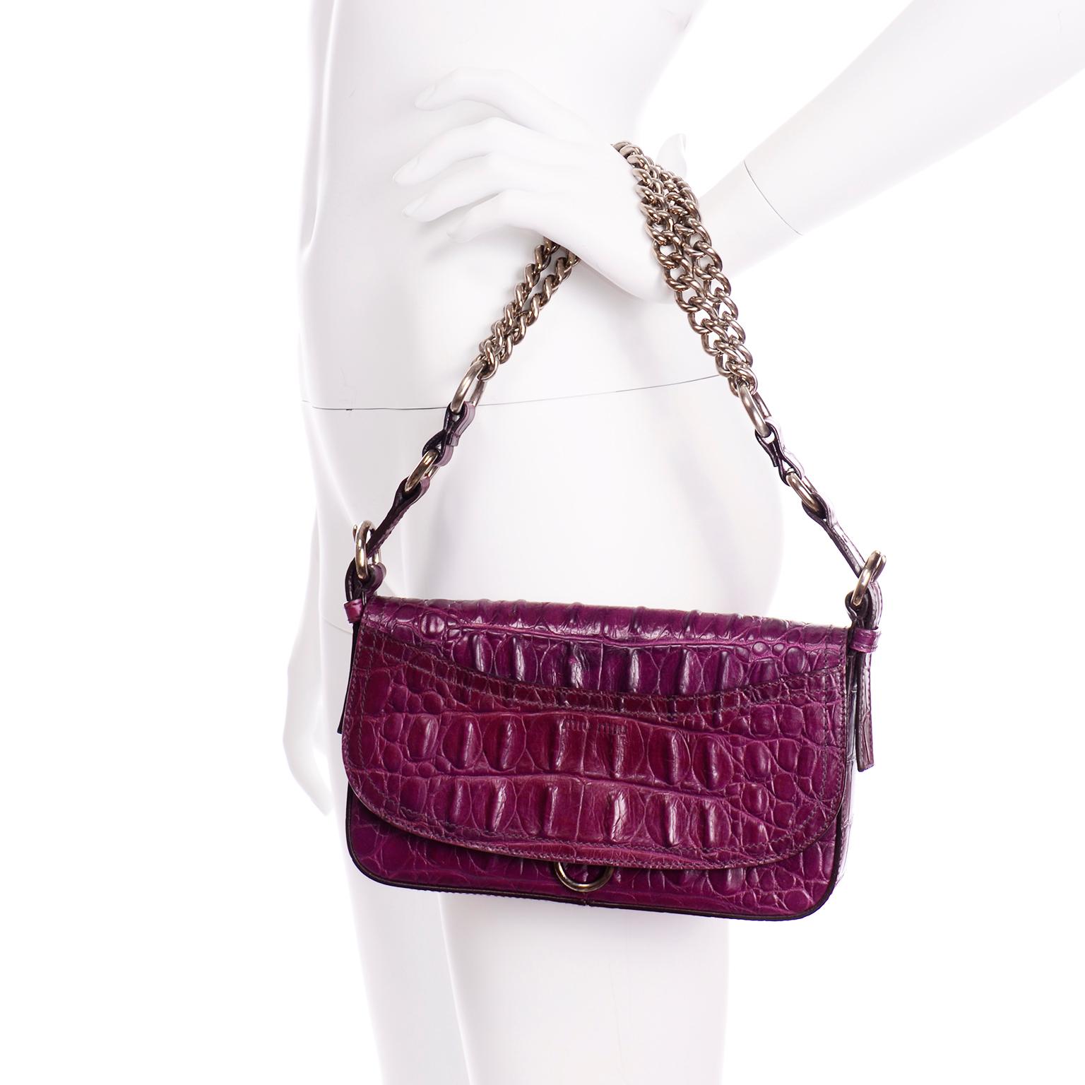 This is an amazing Miu Miu purple crocodile embossed baguette handbag with silver chain hardware. The front of the bag has a small slip pocket on the flap and the bag  is secured with a metal snap button and has a silver hoop at the base of the