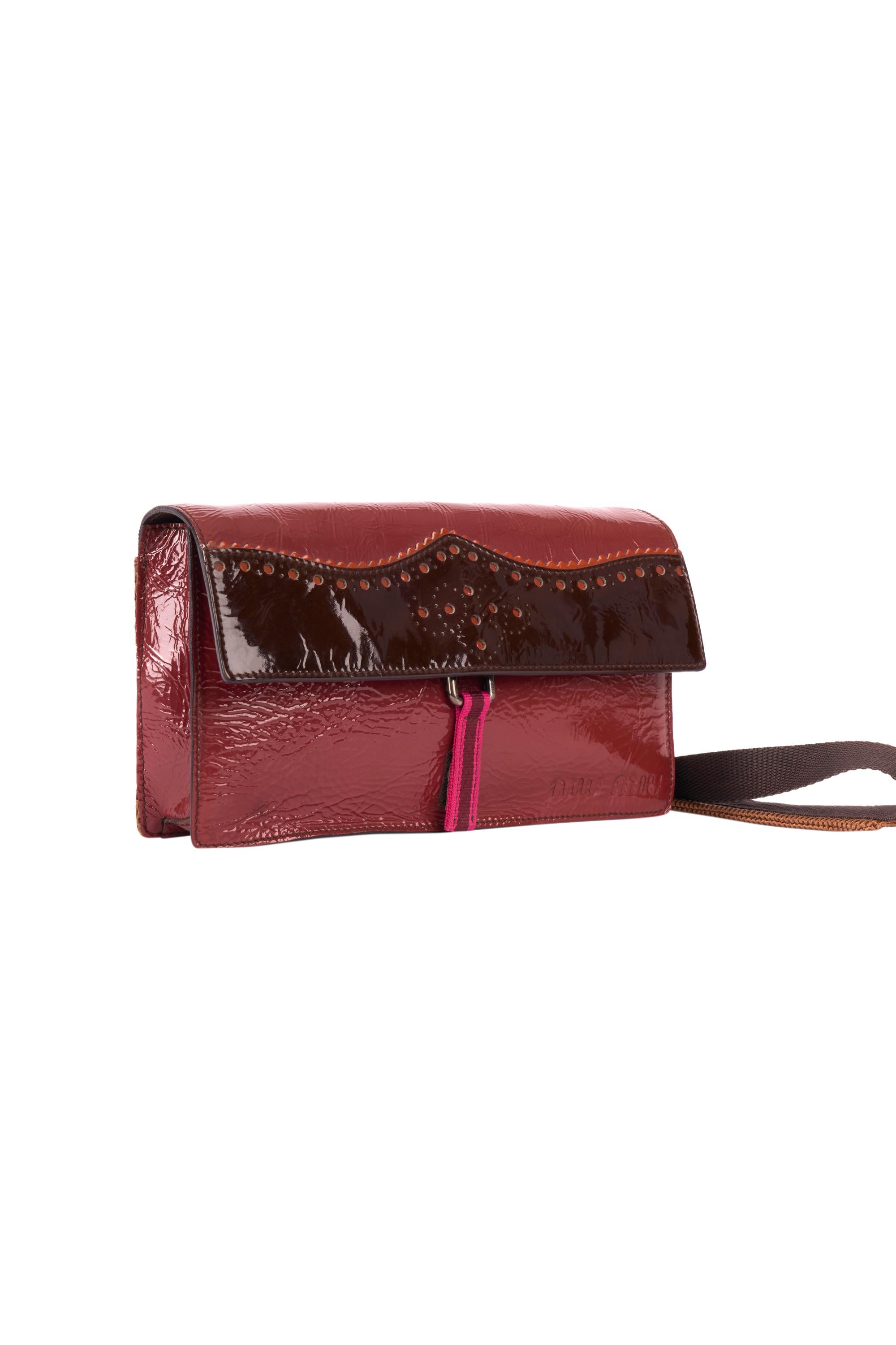 Vintage Miu Miu F/W 1999 chocolate brown patent leather crossbody bag. Feature a brown mesh pocket at the back , dark brown utility straps, black inside lining , Miu Miu logo engrave on the right bottom. Fastens with a small pink and burgundy velcro