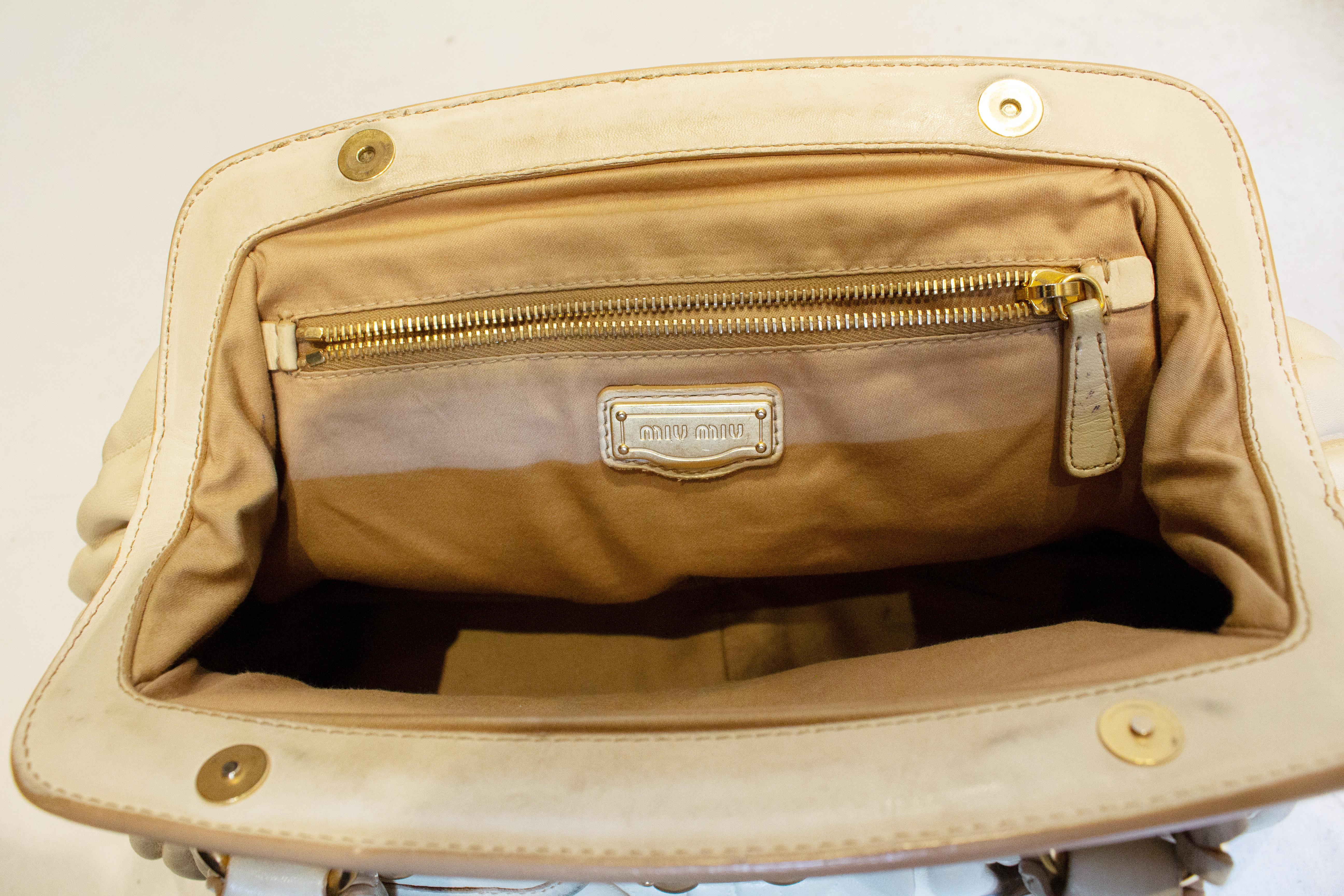 Eine schicke Ledertasche von Miu Miu.  Die Tasche hat einen  öffnung mit Druckknopf oben mit einer Klappe über dem Schloss und Vorhängeschloss.  Sie hat zwei geflochtene Griffe,  eine Innentasche mit Reißverschluss und zwei Außentaschen mit