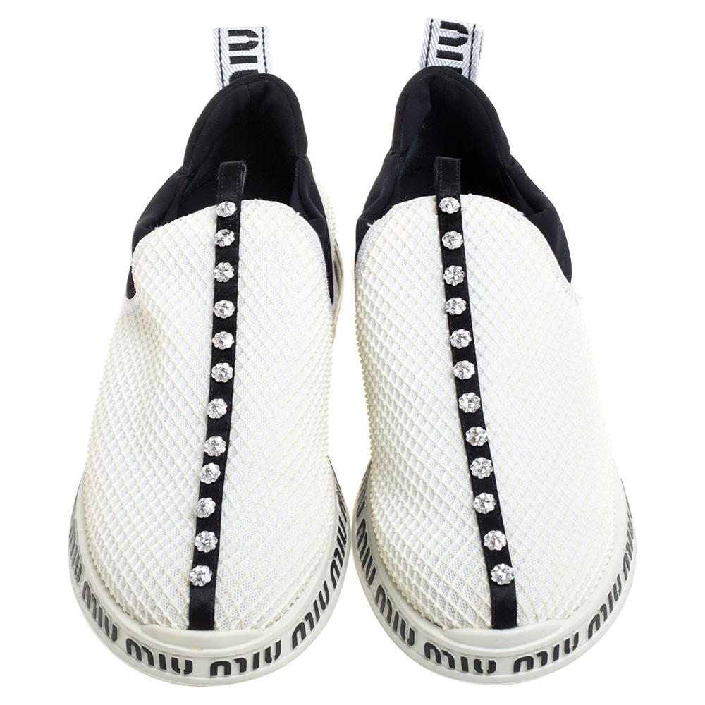 Slip in these Miu Miu sneakers to know how comfort can be blended with style. Crafted with mesh, these white slip-on sneakers have crystal embellishments through the vamps and brand-inscribed, contrasting midsoles. They feature pull tabs on the