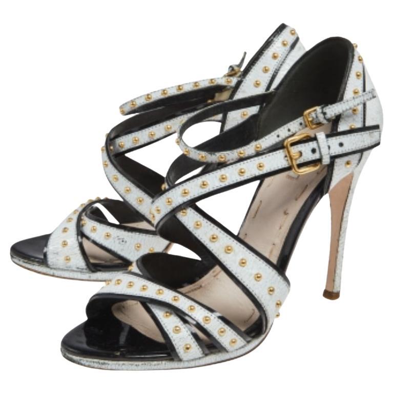 These sandals from the House of Miu Miu are truly a beautiful creation you need to own! Made from white crackled leather, these sandals flaunt studded embellishments throughout with an ankle-strap feature. They are beautified with gold-tone