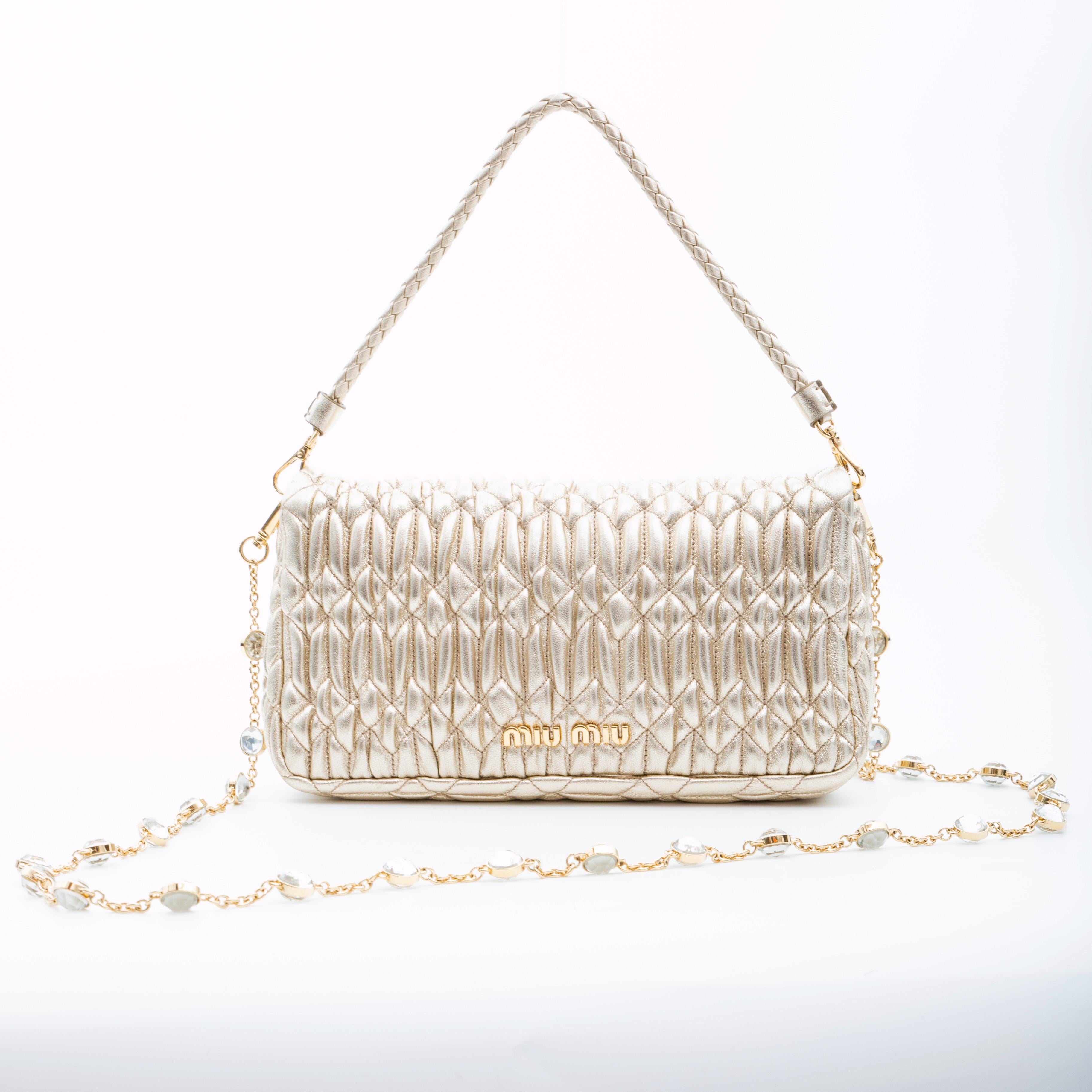 This feminine classic Miu Miu bag is made from the fashion house's signature texture cut from nappa leather with cloquet craftsmanship. The bag features two removable straps including one gold chain shoulder strap with synthetic crystal