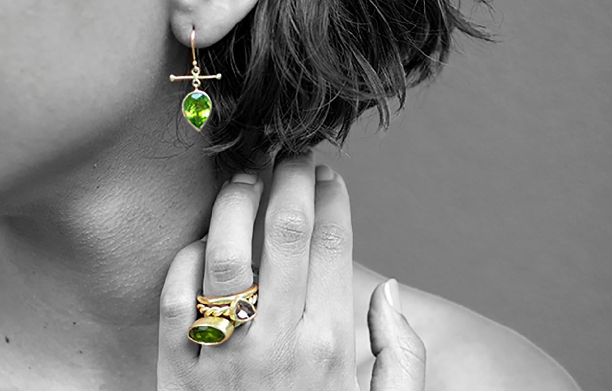 Mix and Match a bright green pear shaped faceted peridot pairs with an oval rutilated olive tone peridot in these one-of-a-kind earrings.   The Peridot is bezel set in 18K recycled gold with my signature 'cross bar', inspired by Victorian watch fob