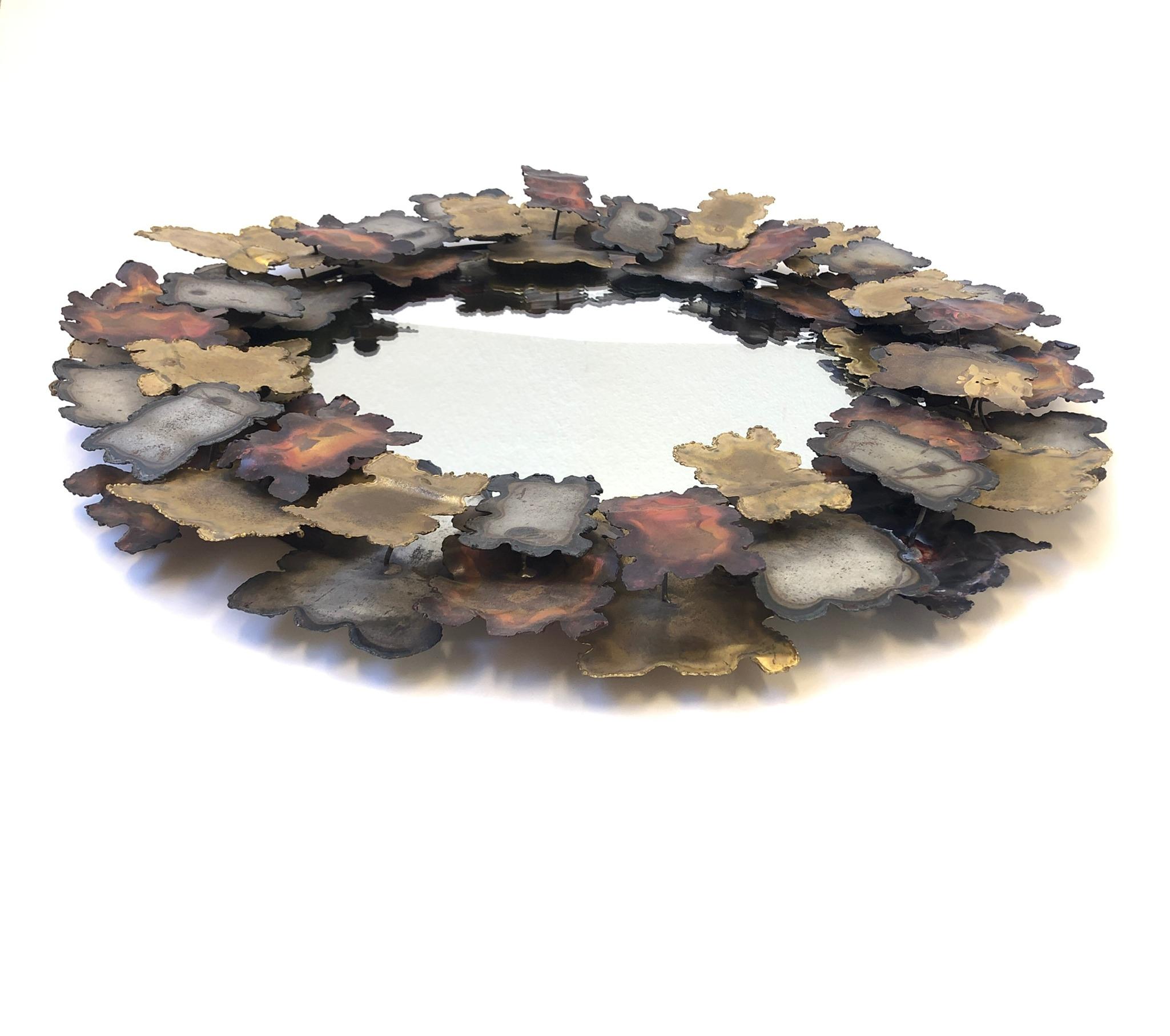 A beautiful round mix metal Brutalist wall mirror in the manner of Silas Seandel. The Mirror frame is constructed of tour cut steel, brass and copper. The Mirror shows some age consistent with age.
Dimensions: 24” diameter 1.5” deep.