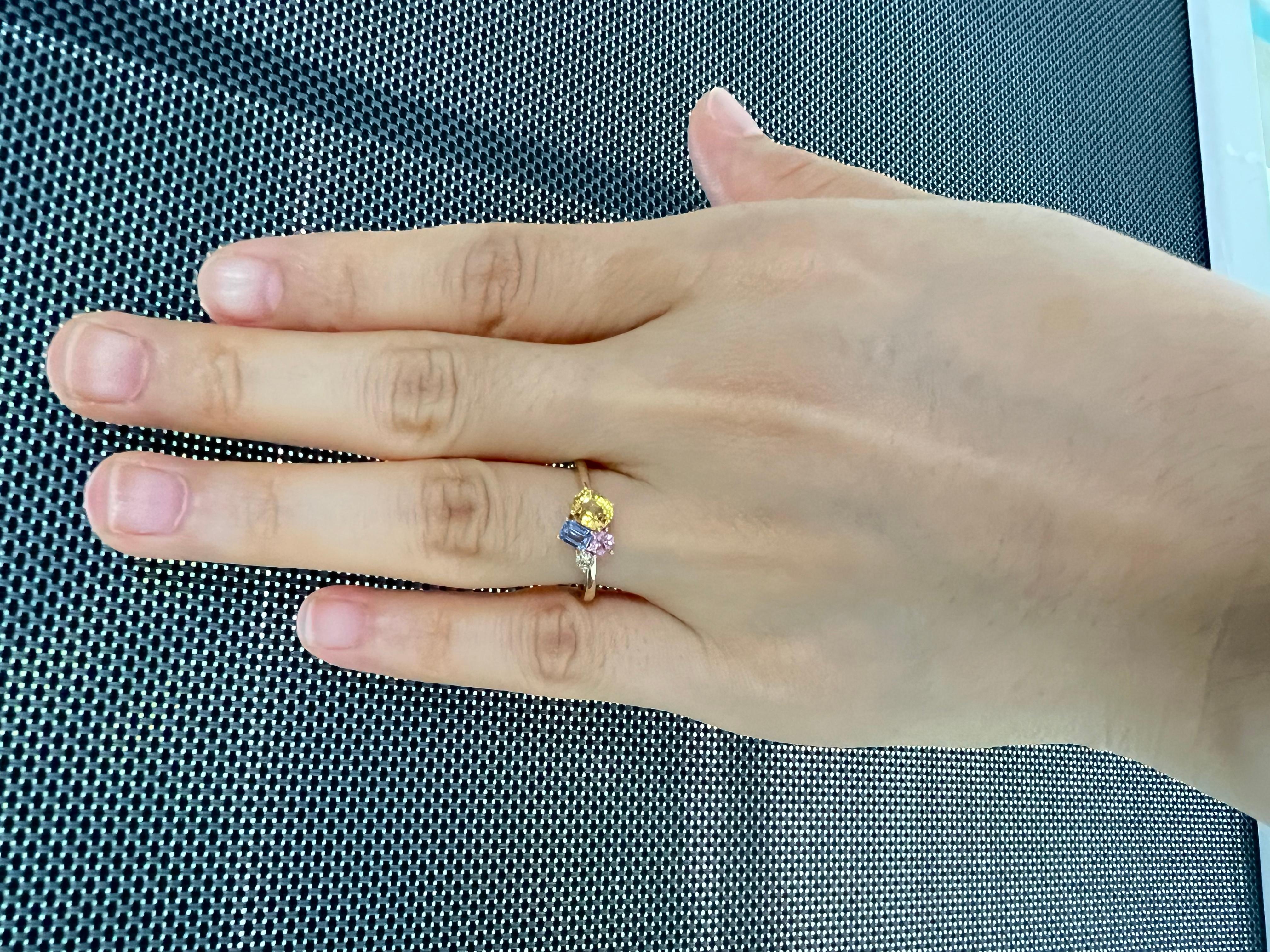 Eleva tu colección con este impresionante anillo de oro amarillo de 14 quilates, una obra maestra de artesanía y vibrante elegancia. Con un cautivador diseño en racimo, esta pieza exhibe tres zafiros de fantasía que suman 1,29 quilates, sus ricos