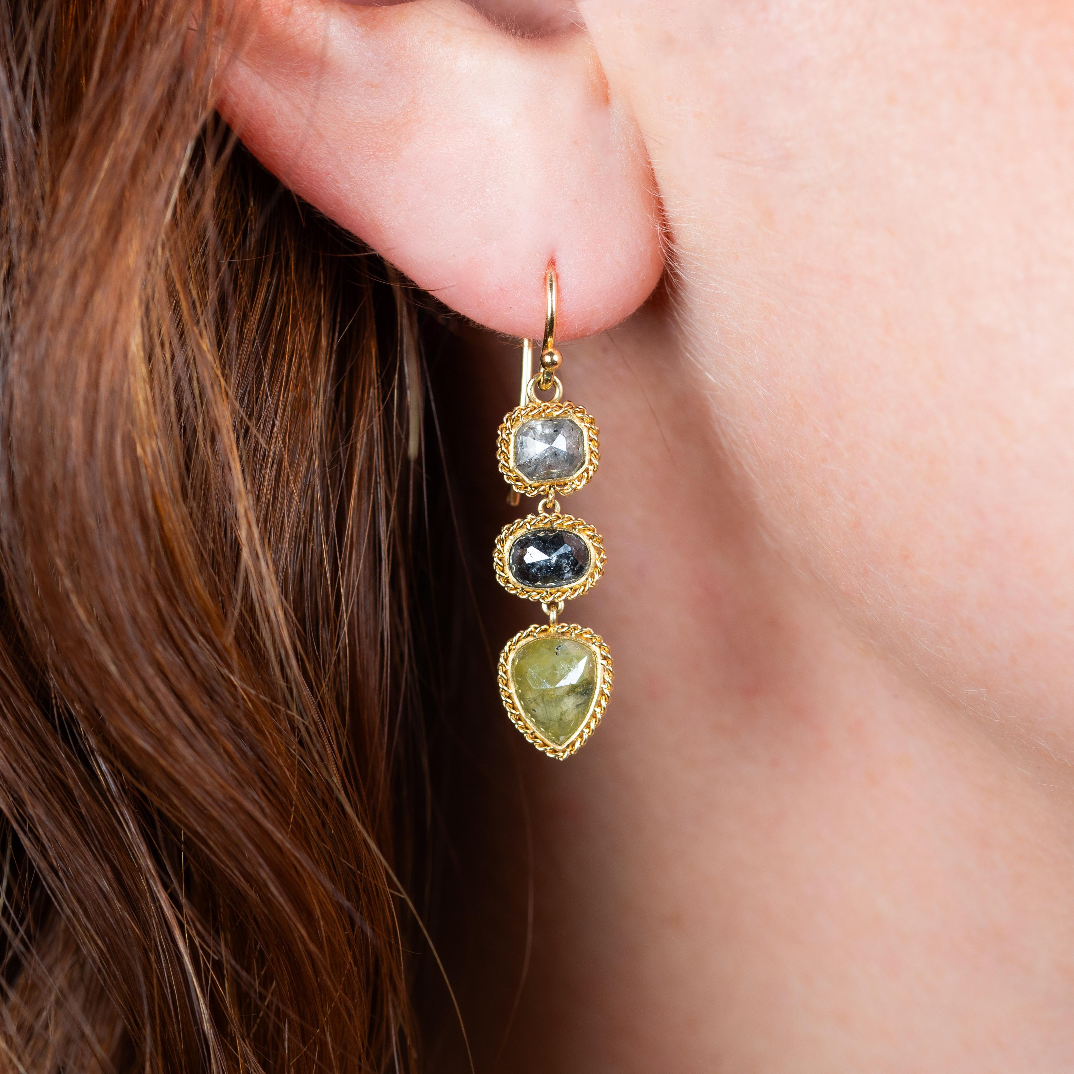 These earrings feature a trio of Diamonds in a variety of remarkable colors and shapes. Each Diamond is naturally colored, meaning it came out of the Earth in this beautiful hue. These one-of-a-kind stones are set in 18K yellow gold