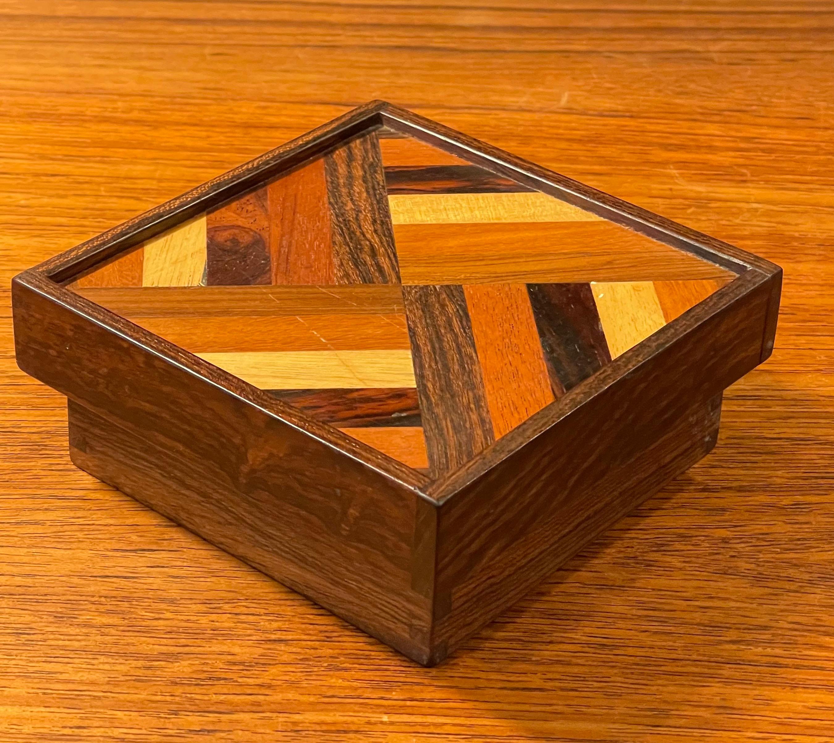 A gorgeous mixed exotic woods trinket box by Don Shoemaker for SeÑal of Mexico, circa 1970s. The box has a removable lid and an incredible weave design of mixed inlaid woods including cocobolo, rosewood, jacaranda and mahogany. The box measures 5